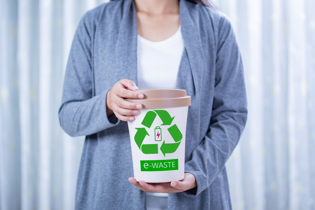 Woman holding electronic waste bin, E-waste concept.