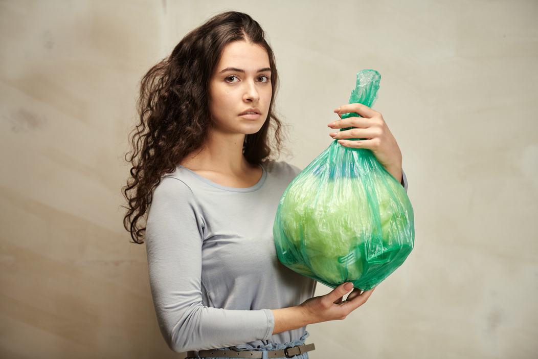 A Woman Holding Green Plastic Bag with Garbage