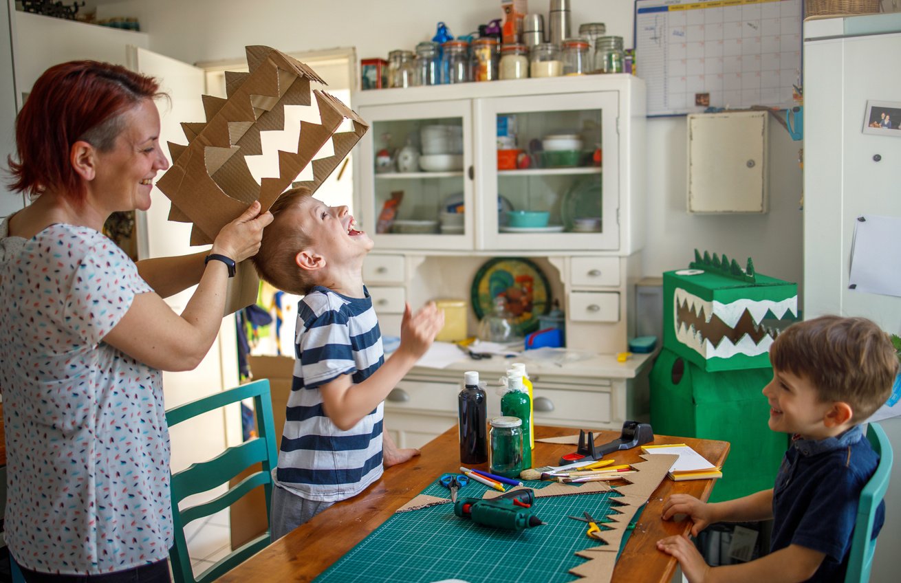 Mom and kids making a cardboard dinosaur costume